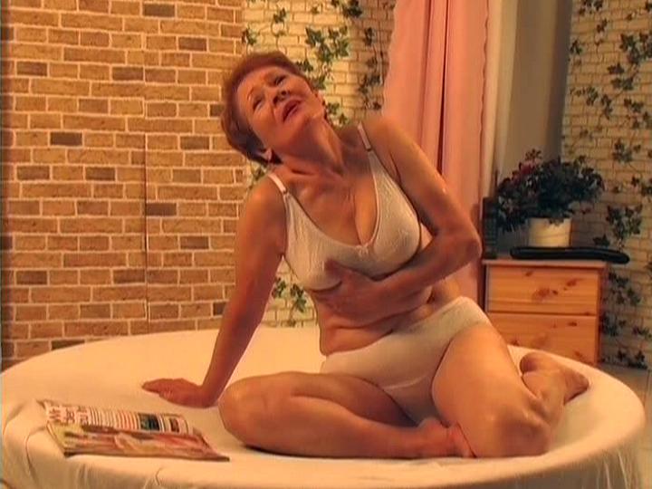 Grandma Nathalie on the couch sucking deeply on a thick black dildo with focused hunger